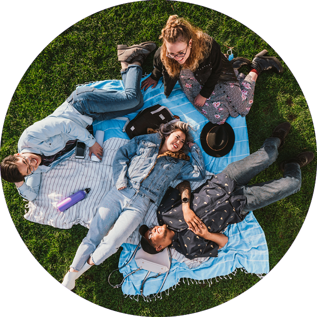 Three young adults laying on towels in a park