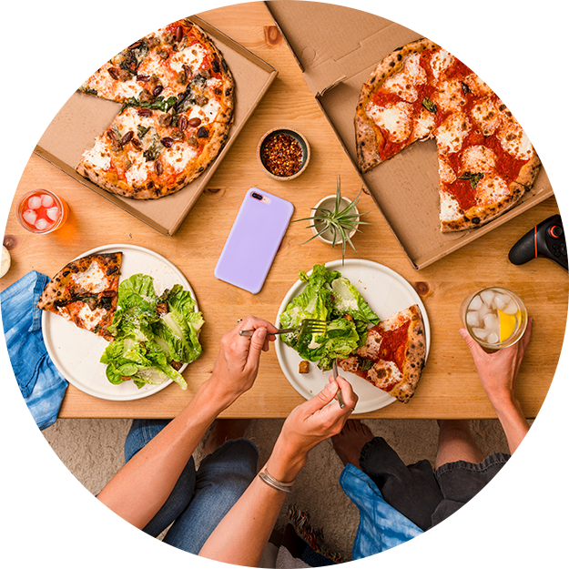 Friends share pizza and salad on coffee table