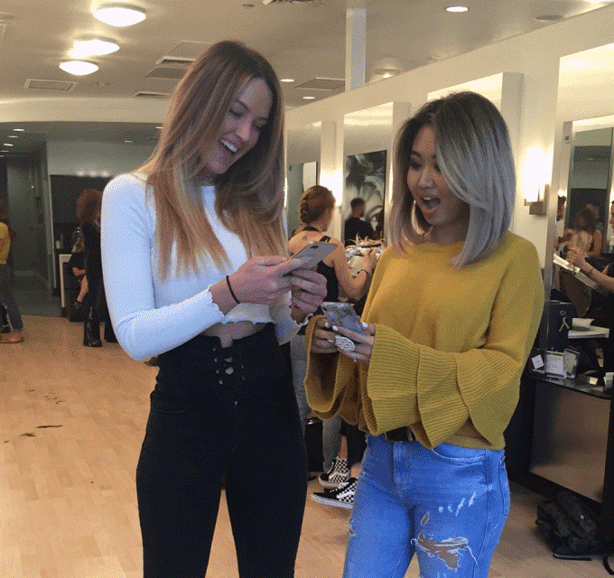 two women looking at phones in a salon and smiling