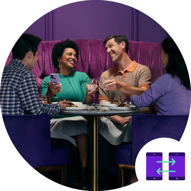 a group of friends sits around a table holding drinks